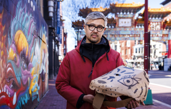 Asian American man with glasses and red jacket holding paper tiger mask in DC Chinatown