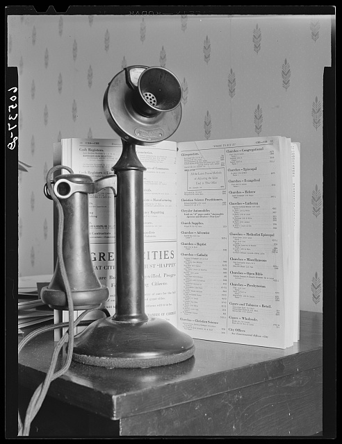 A black and white photograph of a telephone and directory in 1940