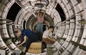 A color photograph of three women working together in a fuselage